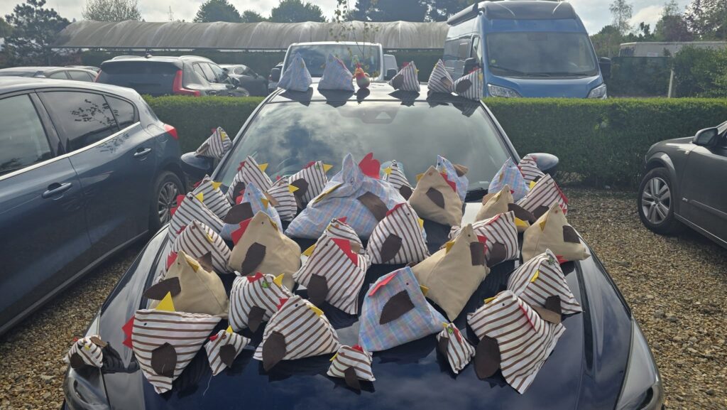 Photo of a car covered with handmade chickens made from recycled materials